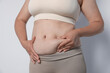 © New Africa - Woman with excessive belly fat on light background, closeup. Overweight problem