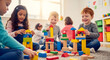 © Mathew - A happy diverse group of preschool children sit on the floor together building towers with colorful wooden blocks