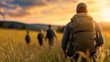 © YURY YUTY - Group of hikers exploring a vast grassland during sunset near scenic hills in summer