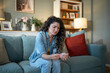 © Migma_Agency - Sad woman checking pregnancy test sitting on sofa at home