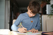 © ulza - A portrait preteen boy draws with pencils at the table in the kitchen at home. Generation Z. Happy childhood.