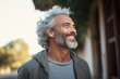 © nsit0108 - Portrait of a happy mature man with gray curly hair and beard smiling and looking away, enjoying a sunny day outdoors