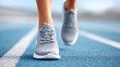 © jes2uphoto - Closeup of person running on blue track wearing gray running shoes, showing motion and athletic activity outdoors