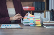 © Kritdanai - Organized Work: A dedicated professional meticulously organizes a stack of documents adorned with colorful sticky notes, symbolizing focus and efficiency. A calm desk scene.