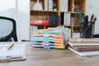 © Kritdanai - Organized Workspace: A neat and organized desk workspace featuring a stack of documents, notebooks, and stationery, conveying a sense of efficiency and productivity.
