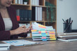 © Kritdanai - Analyzing Documents: A focused professional delves into a detailed review of essential documents, showcasing dedication and precision in the realm of business and administration.