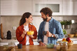 © Stockphotodirectors - In a bright and modern kitchen, a couple happily shares breakfast. The woman holds a bowl of cereal, while the man enjoys a warm beverage, creating a cozy atmosphere.