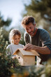 © SolaruS - Heartwarming image of a father and daughter building a birdhouse together outdoors. Captures family bonding, learning, nature, and home improvement. Use for lifestyle content.