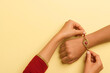 © Aloha Clicks - Close-up of Sister Tying Rakhi to Brother's Hand on Pastel Yellow Background