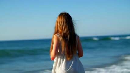 Wall Mural - Woman in white dress walking along the tranquil beach at sunset