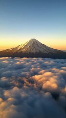 Wall Mural - Snowy mountain peak over golden clouds at sunrise, natural serenity