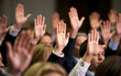 © jendralbiribiri - A group of people raising their hands signifies agreement, participation, or a vote in a business meeting or democratic process.