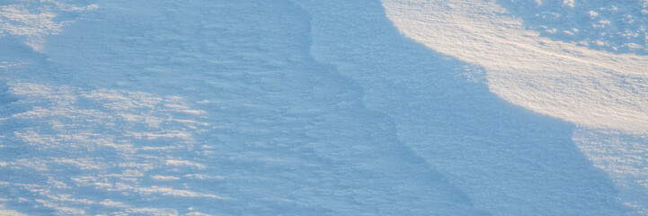 Wall Mural - Beautiful winter background with snowy ground. Natural snow texture. Wind sculpted patterns on snow surface. Wide panoramic texture for background and design.