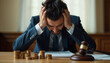 © Anuyj - A sad man faces the burden of paying a penalty fine for legal violations, highlighted by a law gavel resting on a stack of coins