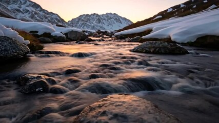 Wall Mural - scenic video of a mountain stream flowing through a snowy landscape with rocky foreground and mounta