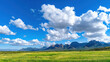 © Chineewan Somsap - Stunning landscape vista featuring lush green fields under bright blue sky adorned with fluffy white clouds, creating serene atmosphere