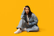 © Pixel-Shot - Beautiful young Asian woman in stylish denim clothes sitting on yellow background