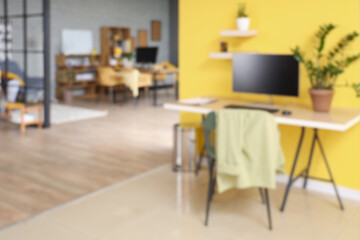 Wall Mural - blurred view of stylish office with desks, plants and yellow wall