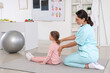 © Pixel-Shot - Female osteopath with little patient stretching and doing exercises in clinic