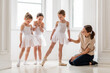 © Cavan Images - teaches young girl ballet in brightly colored studio, children watch.