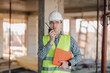 © Ljustina - Construction engineer using walkie-talkie and holding clipboard, inspecting construction site