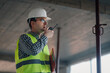 © Ljustina - Construction engineer using walkie talkie and holding clipboard inside building under construction
