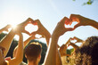© Studio Romantic - Group of young adult youth people doing heart gesture against bright blue sunny sky. Friends hold up hands making heart shapes in sunlight feeling love and connection. Love, friendship, nature concept