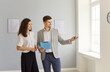 © Studio Romantic - Realtor showing house to a young happy woman looking at the view from the window. Professional real estate agent showing new apartment to female homeowner. Real estate market concept.