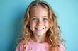 © Vadym - Portrait of smiling young girl with wavy blonde hair, freckles, blue eyes against light blue backdrop. Happy kid, joyful emotions, healthy skin. Positive feelings, childhood beauty.