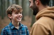 © Vadym - Smiling teenage boy talks with his father outdoor. Father and son enjoy quality time together, communicate with smiles and laughter, forest background adds natural vibe.
