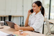 © David - Cheerful business Asian woman freelancer making telephone call share good news about project working in office workplace, business finance concept.