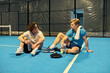 © LIGHTFIELD STUDIOS - Young sportsmen enjoying a break after an intense padel match on the court