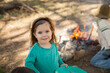 © Austockphoto - Little girl standing outside near the campfire in the bush