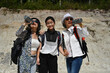 © saltdium - Two senior Asian women and a granddaughter take a break during a hike, smiling and drinking water in the sun. Active lifestyle and bonding across generations