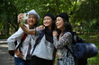 © saltdium - A smiling granddaughter takes a cheerful selfie with her two grandmothers during a hiking adventure in the park. Happy multi-generational travel moments