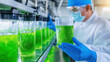 © Somporn Na Ubon - Scientist in laboratory examines glass container filled with green algae, showcasing focus on research and innovation in biotechnology