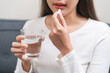 © KMPZZZ - Dietary supplement, healthy diet positive asian young woman hand holding pill capsule, take vitamin in mouth for beauty skin hair, taking medicine with glass of water at home, pharmacy and health care