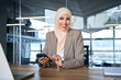 © Stock 4 You - Smiling young indian woman in hijab holding smartphone sitting in office working online at desk, looking at camera portrait. Middle Eastern muslim businesswoman manager ceo using cell phone mobile app