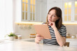 © New Africa - Woman with modern tablet at white marble table in kitchen, space for text