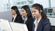 © StocksJust4You - Three professional and attractive Indian women wear suits and headsets, smiling while working on computers in a bright office - confident customer service assistants in action
