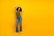 © deagreez - Casual young woman striking a cheerful pose in green top and jeans on yellow background, embodying trendy summer style