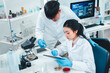 © Irin - Young researchers collaborate on mold sample analysis in a science lab. The male scientist holds a petri dish while the female supervisor examines data. Team discovery and scientific breakthrough.