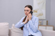 © New Africa - Depressed woman calling hotline for mental health help on sofa at home
