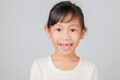© sorapop - Happy kid girl smiles with missing tooth, dentist discusses tooth loss process. Asian child with gap learns about dental care and how new teeth grow naturally. isolated white background