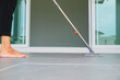 © sorapop - Woman mops the indoor floor, cleaning the front area of her home with a mop and rag. Housewife dedicated to maintaining cleanliness. Represents professional housekeeping and house maintenance concepts