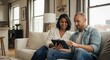 © AlfaSmart - Couple relaxing at home, engaged with tablet technology in modern living room