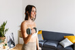 © Xavier Lorenzo - Happy beautiful woman doing exercises with dumbbells at home. Pretty female working out her arm muscles. Healthy lifestyle and sport concept.