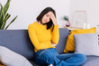 © Xavier Lorenzo - Young woman sitting on sofa at home suffering a headache. Adult female touching forehead having a strong migraine and feeling tired after hard working day.