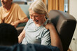 © Maskot - High angle view of male caregiver with hand on shoulder of happy senior woman sitting on armchair at retirement home