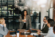 © Maskot - Businesswoman sharing ideas with colleagues sitting around table in meeting